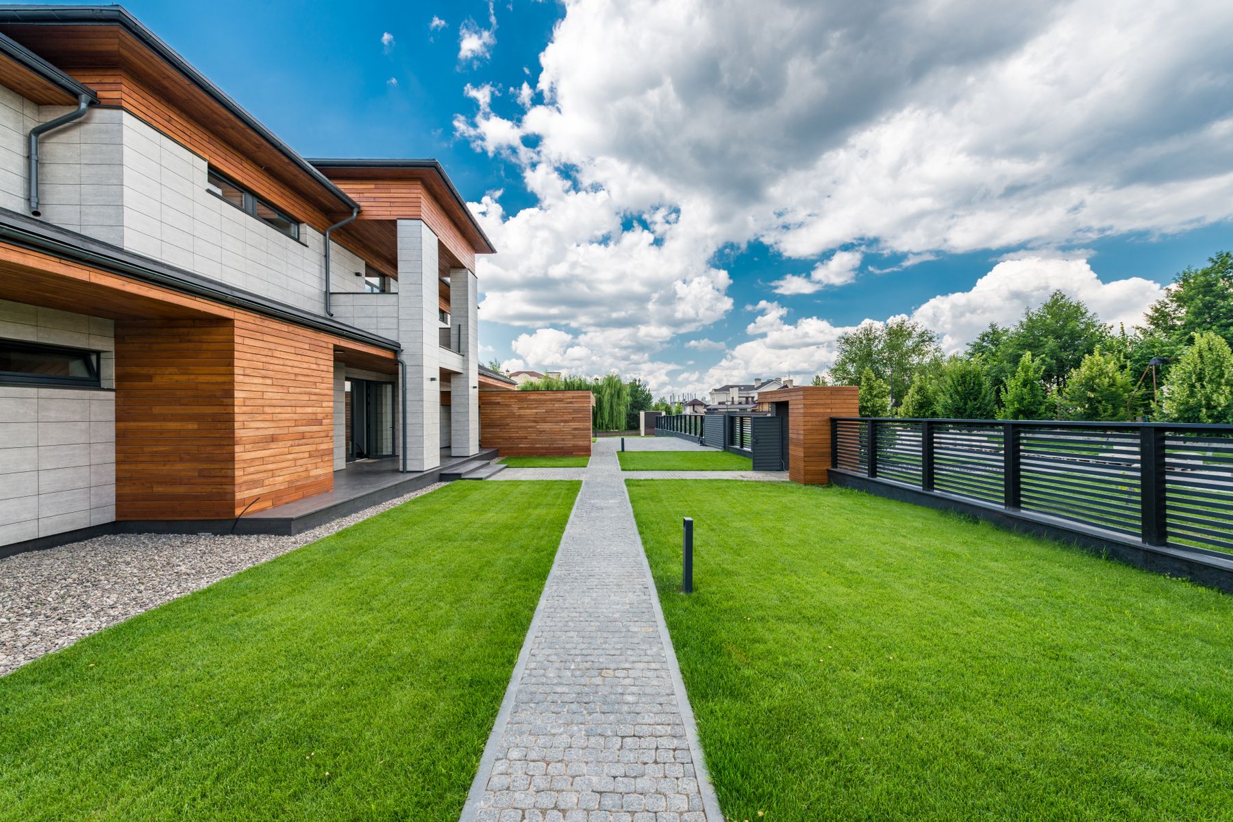 Modern custom home with a wood and stone exterior and a green lawn