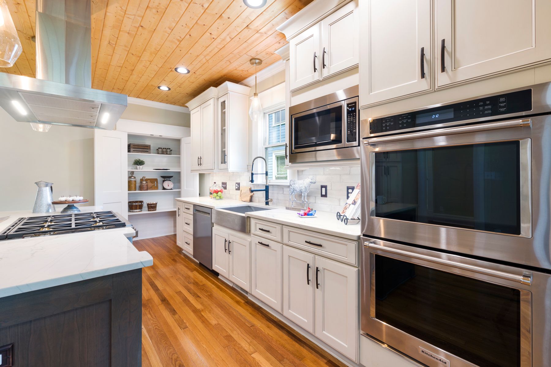 Finished kitchen with white cabinets, warm wood ceiling, and stainless appliances