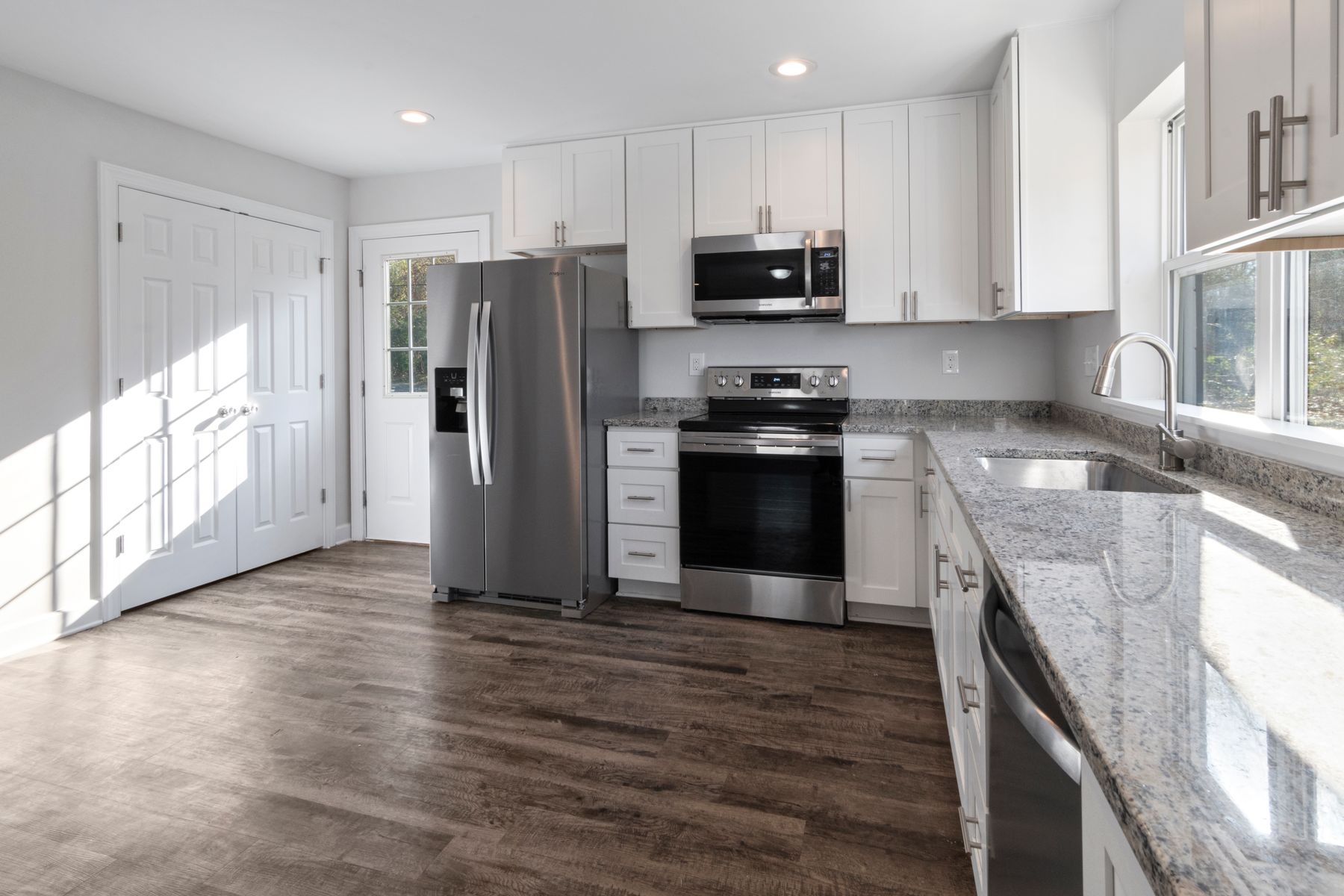 Bright white kitchen with dark wood-look flooring