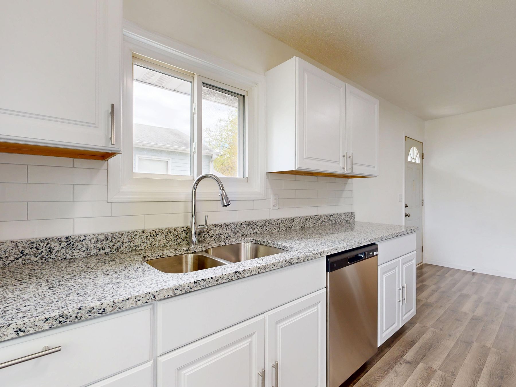 White kitchen cabinets with a granite counter and window over the sink